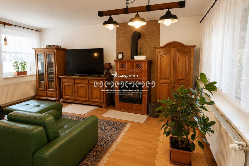 Living room with wood-patterned flooring, green sofa, and wooden furniture in a family house.