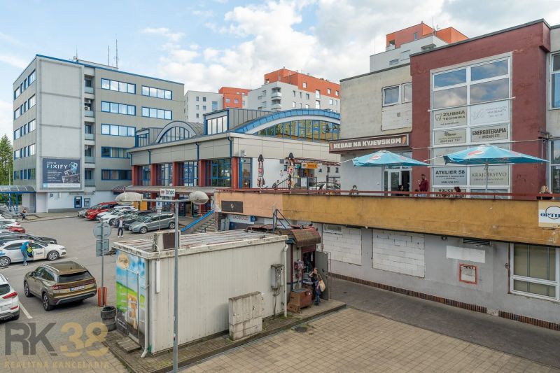 A building in Banská Bystrica with service facilities and a parking lot full of cars.