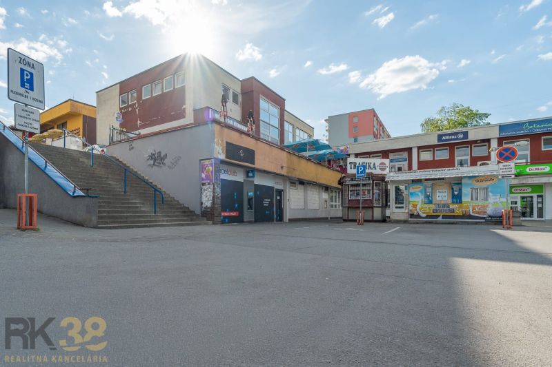 A building in Banská Bystrica with shops and a staircase, sunny day.
