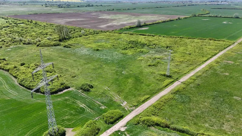Agricultural and forest lands in Zemplínske Kopčany with visible electric poles and a road.