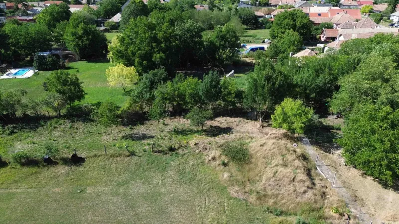 A view of green residential plots in Hronovce, surrounded by trees and grass.