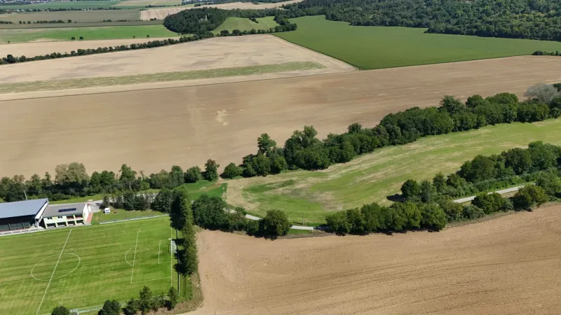Panorama of agricultural and forest landscape near Nová Ves nad Váhom with a football field.