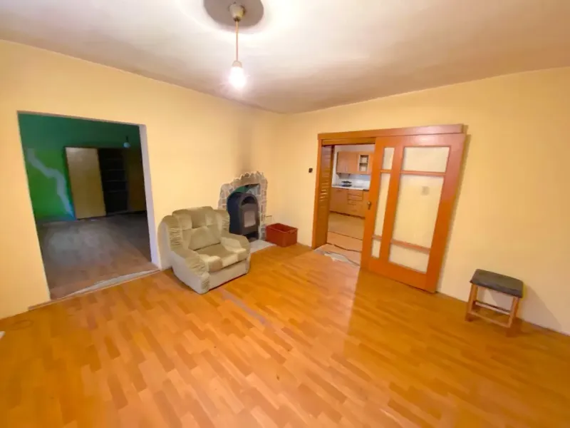 Interior of a family house with a wooden decor floor, a comfortable armchair, and a fireplace.