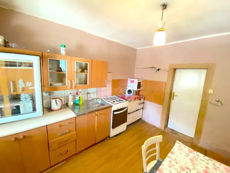 A kitchen in a family house with a wooden decor floor and wooden cabinets.