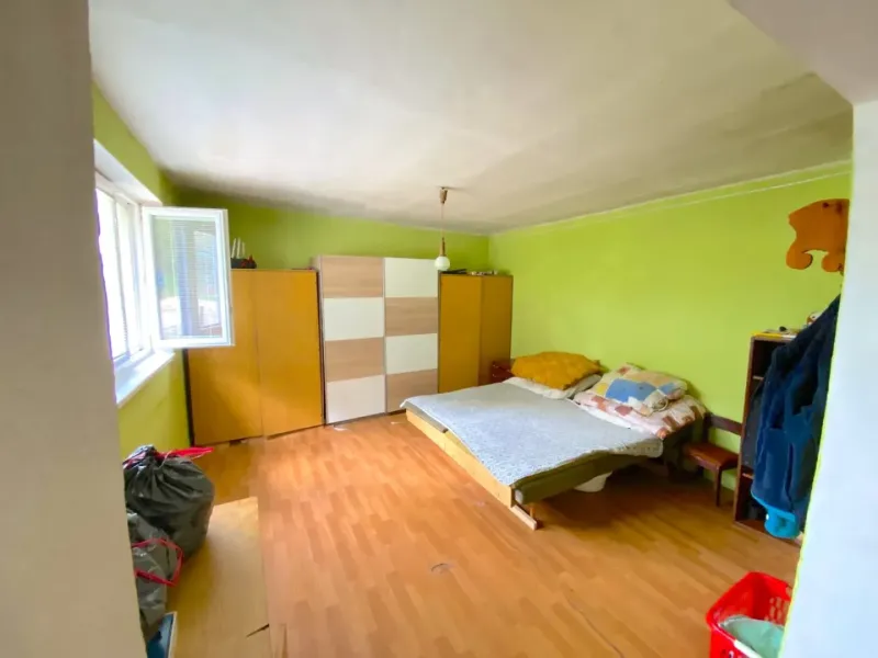 A room in a family house with a wooden decor floor, green walls, and furniture.