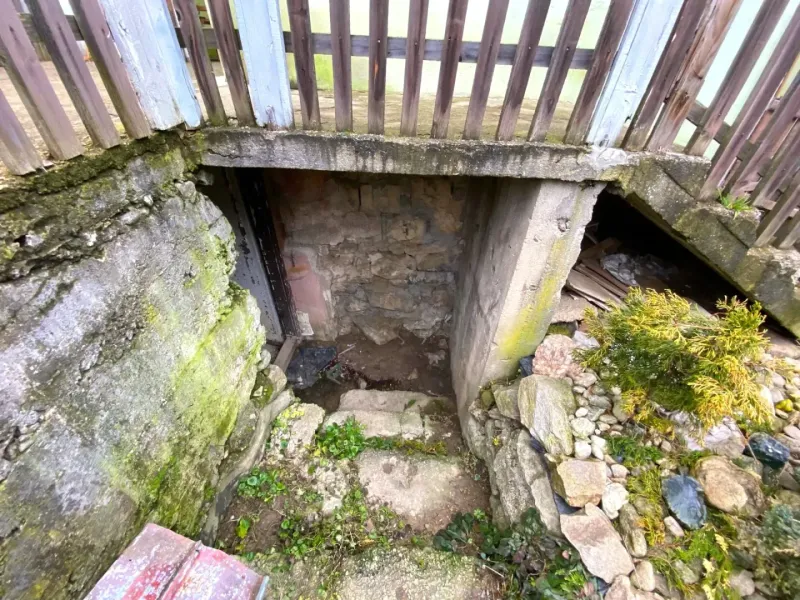 Entrance to the basement of a stone family house in Kokava nad Rimavicou with a wooden fence.