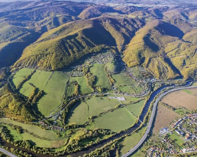 Aerial view of agricultural and forest land in Orovnica with a river and a highway.