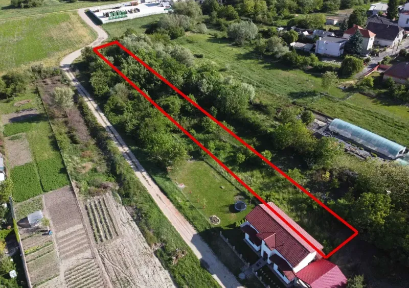 Aerial view of a garden in Branč, outlined by a red line, surrounded by greenery.