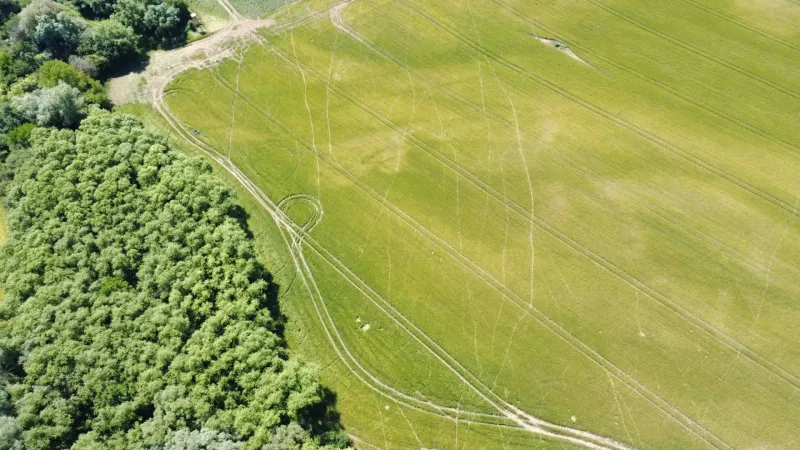 Aerial view of agricultural and forest land in Kozárovce, green landscape with a field.