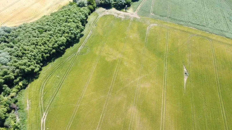 An aerial view of agricultural and forest land near Kozárovce, surrounded by fields and forests.