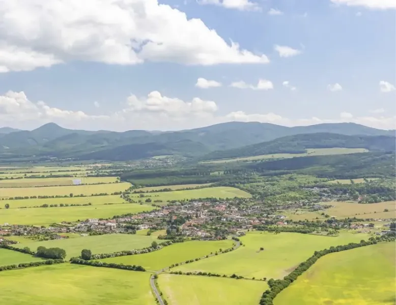 A view of agricultural and forest lands around Jablonové with mountains in the background.