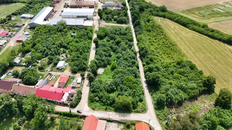 An aerial view of vegetation-covered residential plots in Parchovany, bordered by roads and buildings.