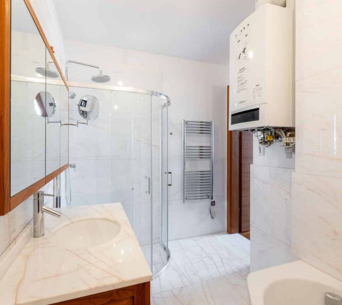 Bathroom in a 2-room apartment with a sink, shower, and water heating.