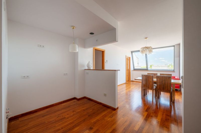 Interior of a 2-room apartment with a wooden decor floor and a dining table.