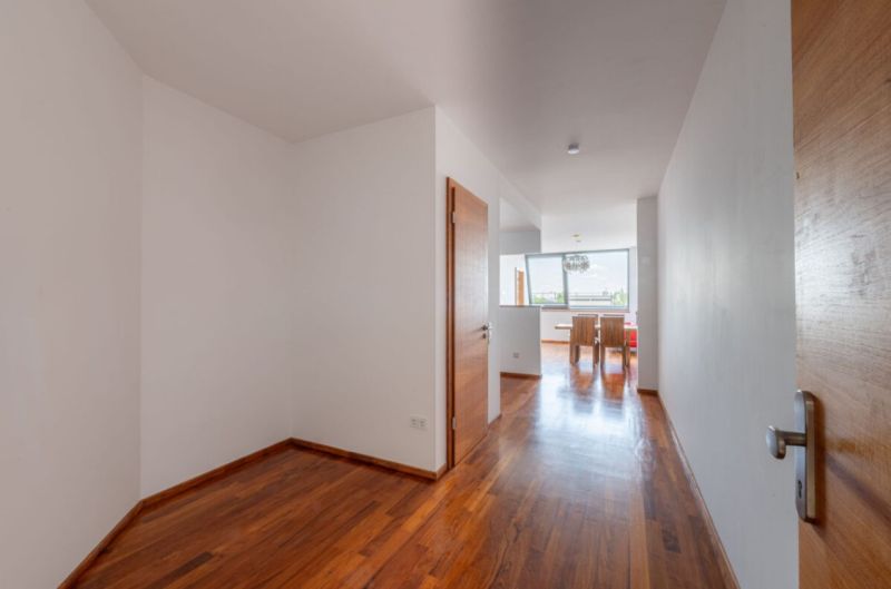 A hallway in a 2-room apartment with a wooden decor floor and a dining area.