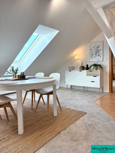 Dining area with a table in an attic 4-room apartment with a large skylight.