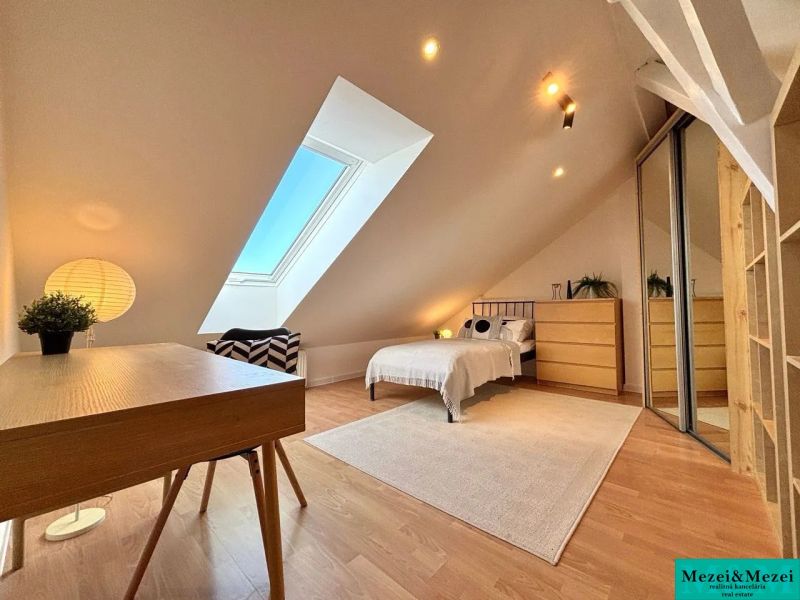 Attic room with a table, bed, and mirrored wardrobe in a 4-room apartment.