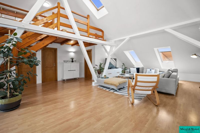 Bright attic living room with a gallery and wooden decor flooring.