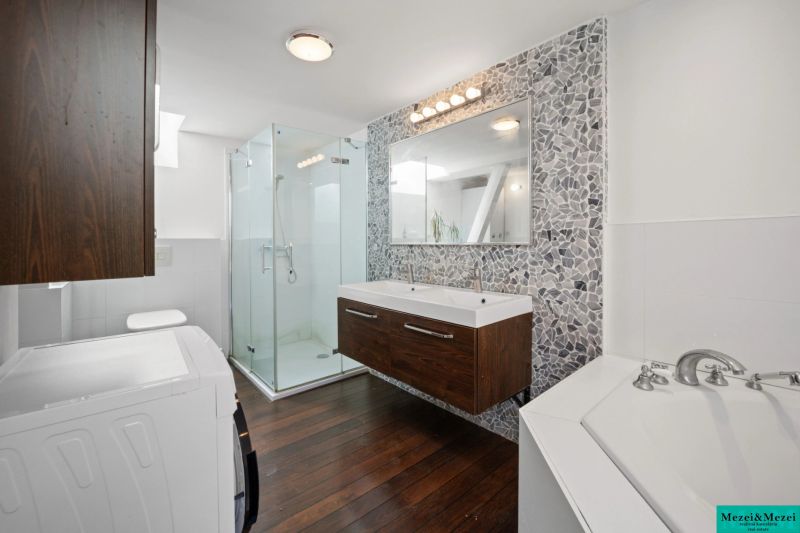A bathroom in a 4-room apartment with a mosaic wall and a floor with a wooden decor.