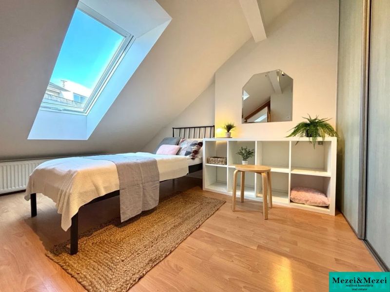Attic room with a skylight, bed, and shelving cabinet, floor with wooden decor.