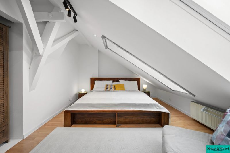 Attic bedroom with a sloped ceiling, wooden decor flooring, double bed.