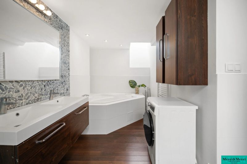 A bathroom in a 4-room apartment with a double sink, a bathtub, and a wooden decor floor.