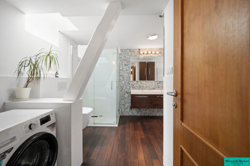 Bathroom with a shower, washing machine, and a floor with a wooden decor in a 4-room apartment.