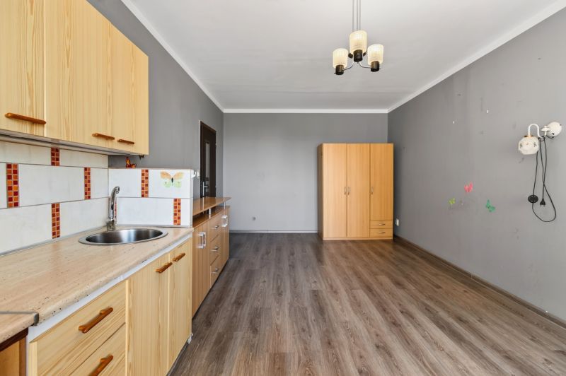 Interior of a 1-room apartment with a kitchen unit, wardrobe, and floor with a wooden decor.