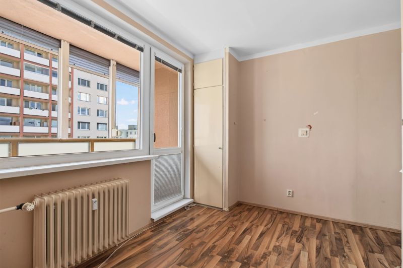 A room with a radiator and a wooden decor floor in a studio apartment.