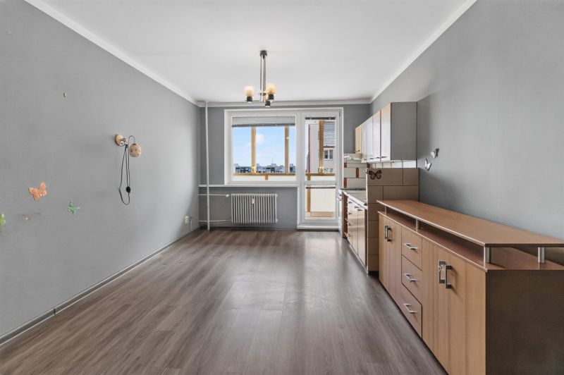 Gray walls, kitchen unit, and wooden decor flooring in a studio apartment.
