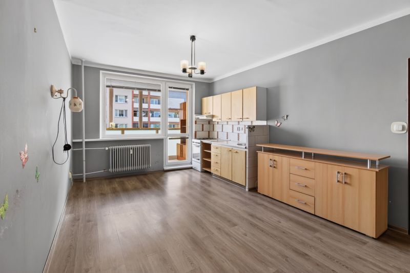 A kitchen in a studio apartment with a wooden decor floor and built-in cabinets.