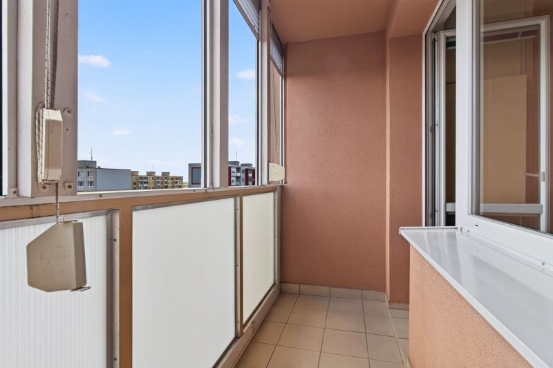 A glazed balcony with a view of the housing estate, part of a one-room apartment.