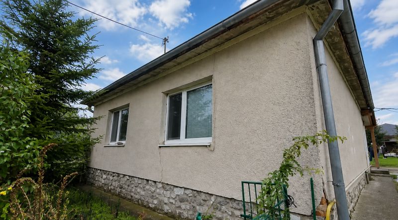 A family house in Veľké Ripňany with a gray facade and a stone plinth.