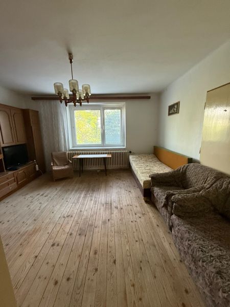 Living room in a family house with a wooden decor floor and older furniture.