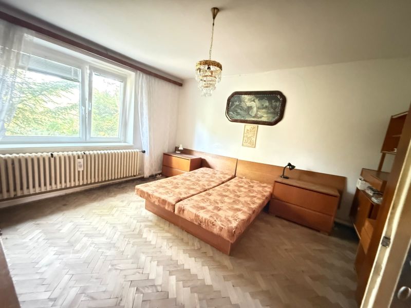 Bedroom in a family house with parquet flooring and a large window.