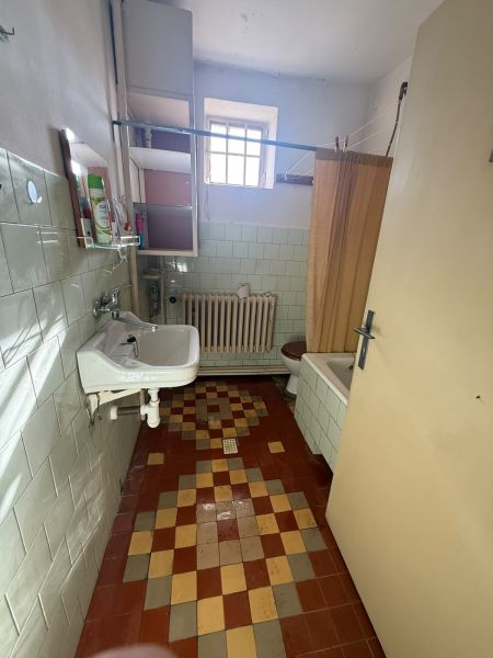 A bathroom in a family house with a colorful floor, a sink, and a shower curtain.