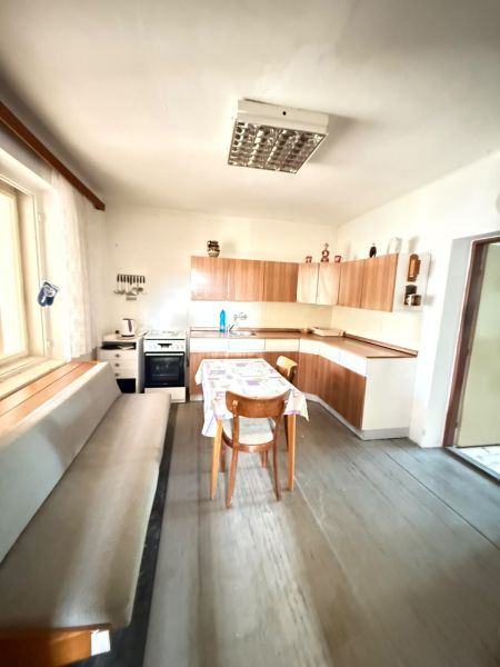 A kitchen in a family house with a wooden decor floor and simple furnishings.