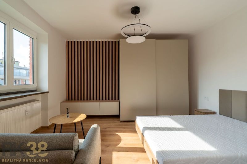 A one-room apartment with a wooden decor floor, a bed, and wardrobes.