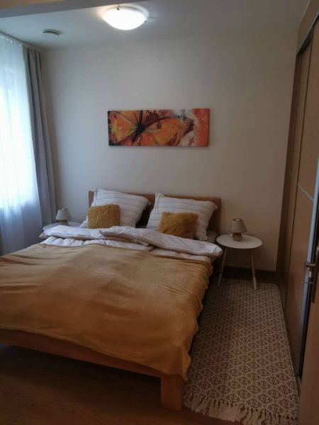 A bedroom in a family house with light walls, a painting, and a wooden bed.