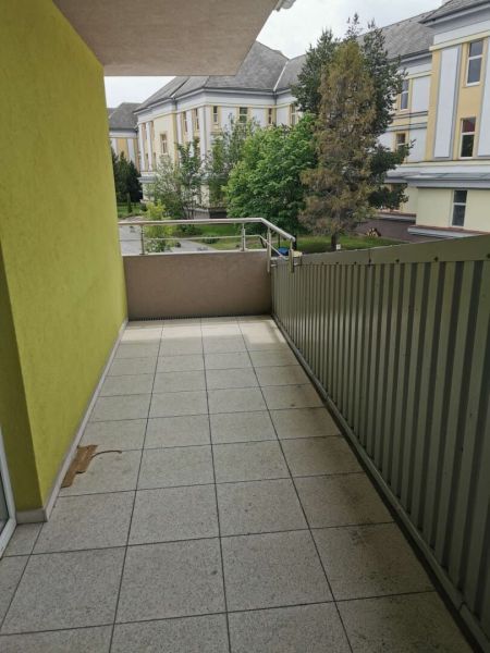 A balcony of a family house in Poprad with a view of the green yard and buildings.