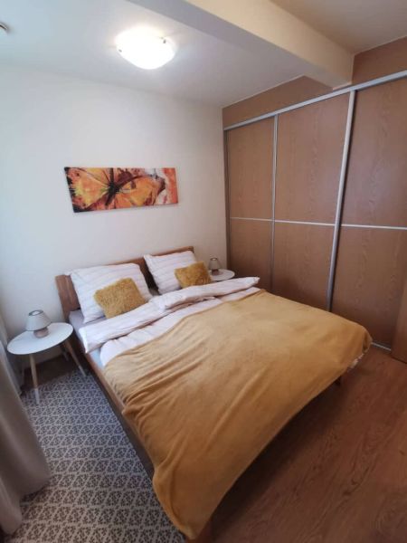 Bedroom in a family house with a bed, painting, and wooden decor flooring.