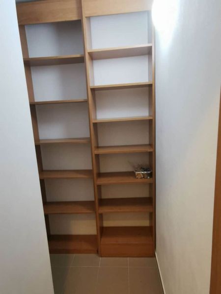 Storage space in a family house with wooden shelves and tiled floor.
