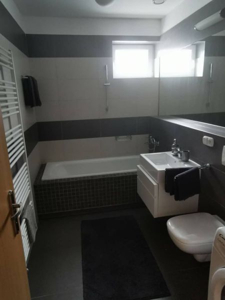 A bathroom in a family house with a bathtub, sink, toilet, and striped tiles.