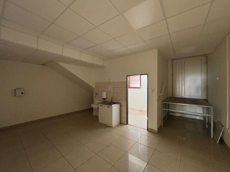 Interior of commercial premises with a sink, tiles, and entrance to another room.