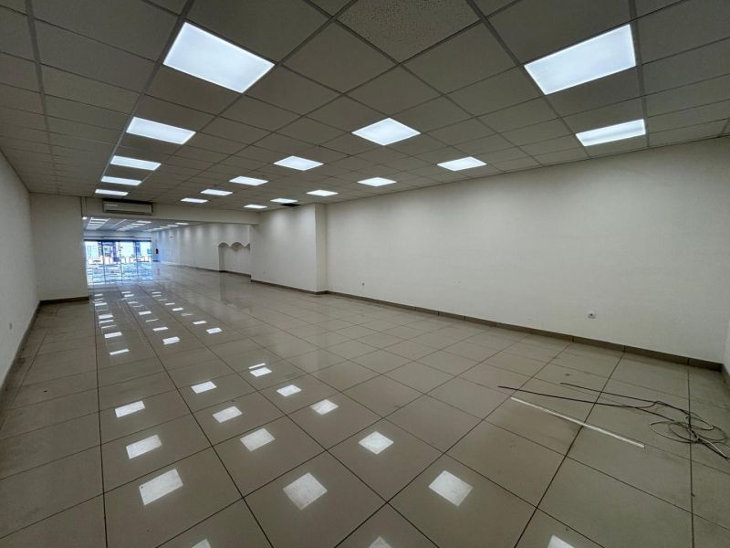Commercial premises with a white ceiling and lighting fixtures, tiles, spacious interior.