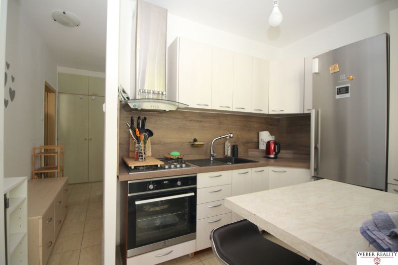A kitchen in a 2-room apartment with white cabinets and stainless steel appliances.