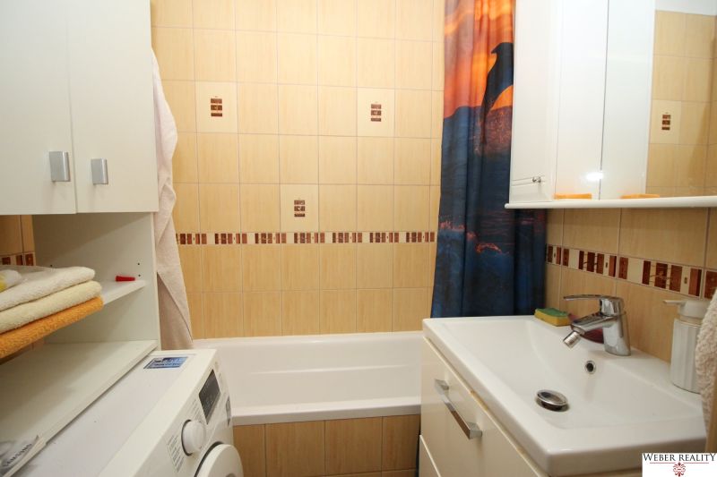 Bathroom in a 2-room apartment with a washing machine, bathtub, and sink.