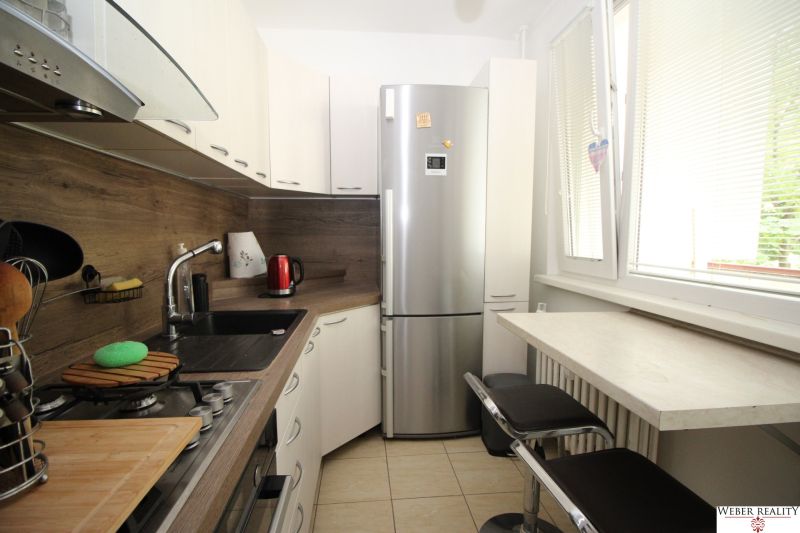 A kitchen in a 2-room apartment with a corner unit, a refrigerator, and a bar counter.