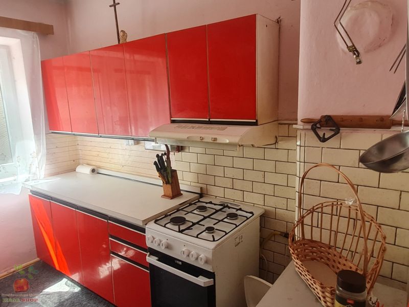 A kitchen in a family house with older red furniture and a gas stove.