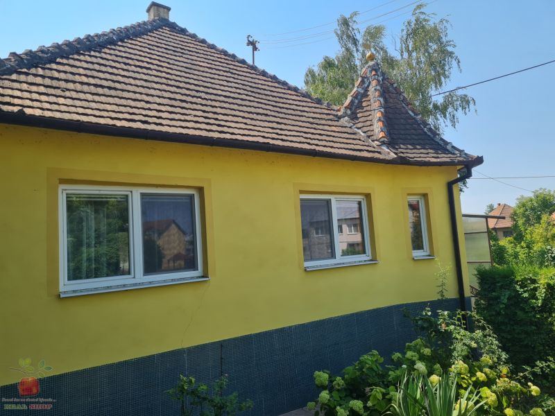 A family house in Komjatice with a flower garden and a yellow facade.